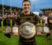 Rugby player holding a custom MVP championship belt above their shoulder, celebrating an outstanding performance on the field.
